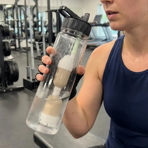 Person holding a water bottle in a gym setting using FlavaFil to trust the water fountain at the gym 