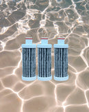 Three pleated cylindrical filters using Ahlstrom Disruptor media with integrated activated carbon on a reflective water surface background