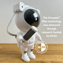 Astronaut toy holding Flavafil MAX water filter with text about Disruptor filter technology and NASA funding on a wooden surface.
